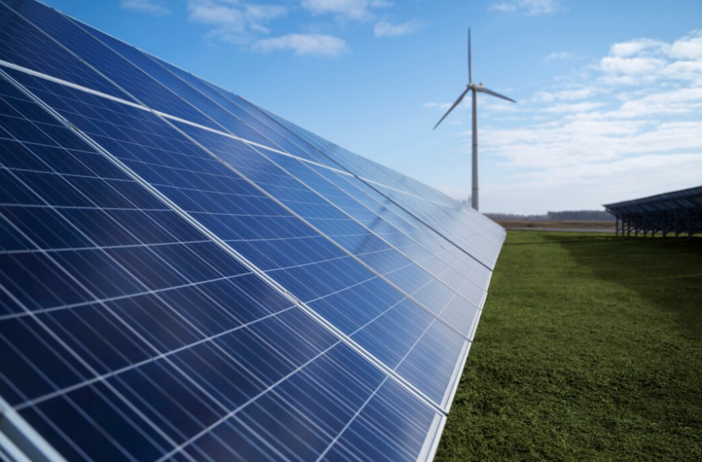 Solar panels and wind power plant outside, green grass below