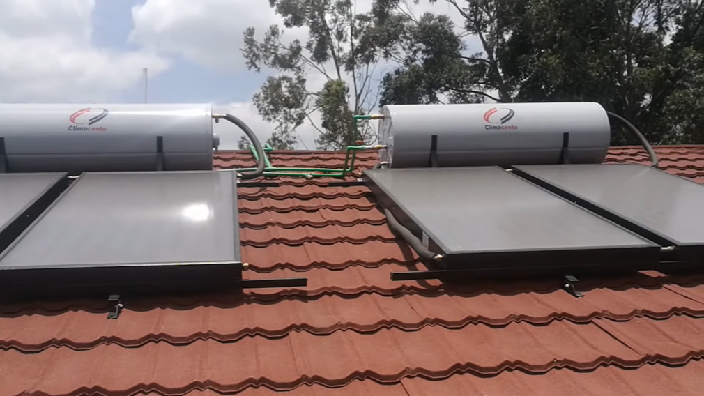 Rooftop passive solar water heating setup with 'Climacento' storage tanks on a terracotta-tiled roof