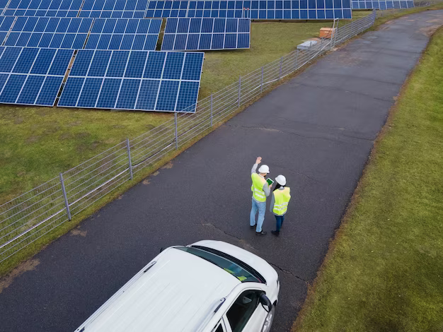 A girl and a man in helmets stand in front of solar panels, top view