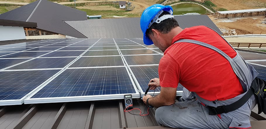 a man installs a solar panel on the roof of a building