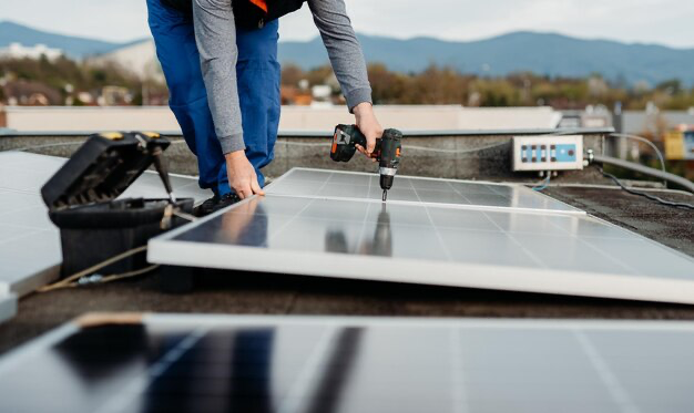 Man installing solar panels using a drill