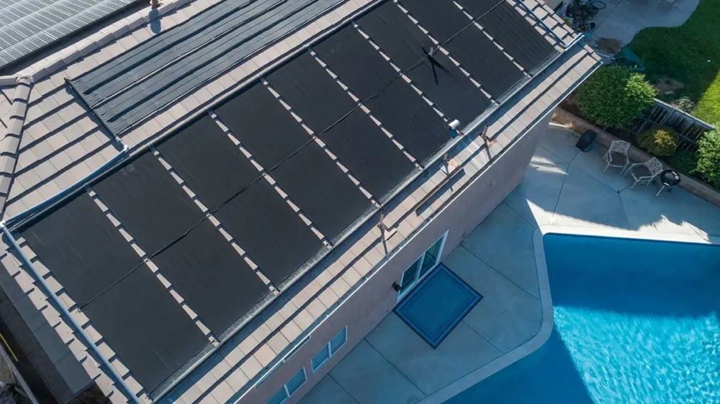 Solar panels on the roof of the house, next to the pool