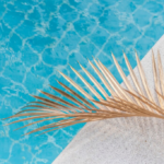 Blue swimming pool with golden palm leaf under the sunlight