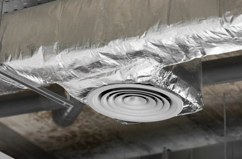 a side view of the ventilation wrapped in shiny foil, the pipes on the dark ceiling