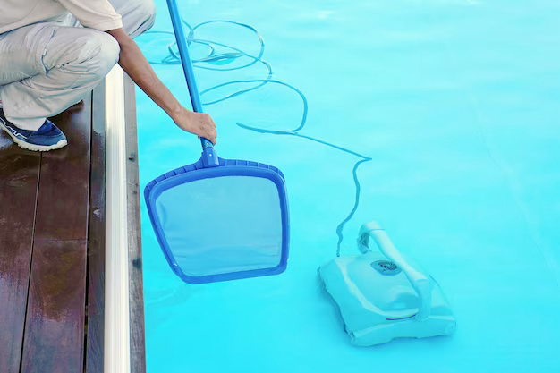 A man cleans a pool at the bottom of which there is a heater