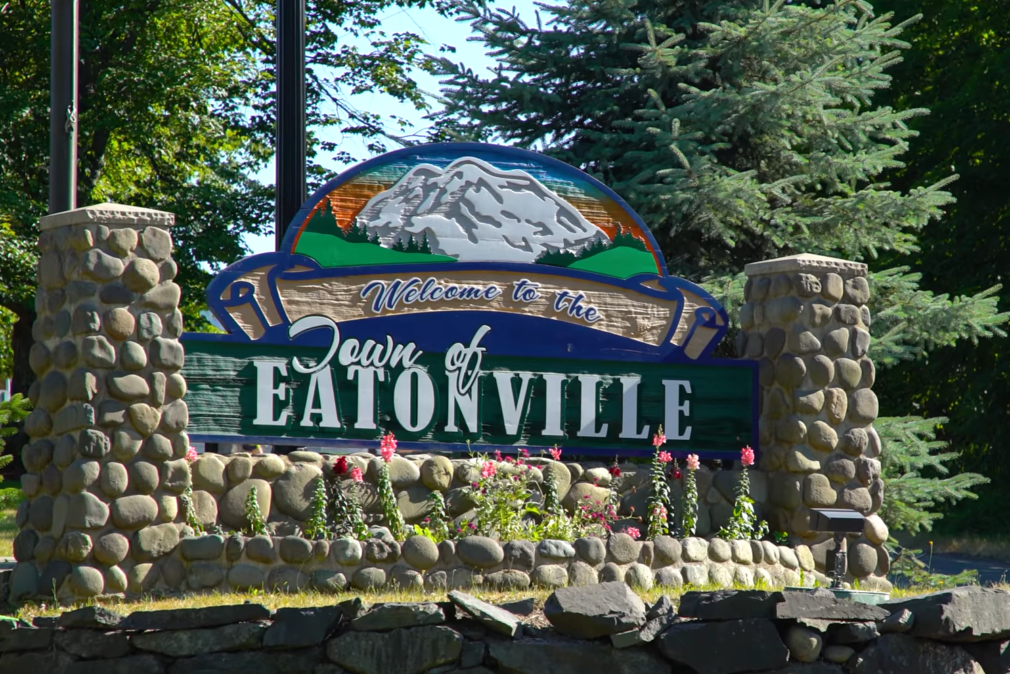 welcome to the town of Eatonville words and picture of the mountains on it, two columns of stones, and trees above it